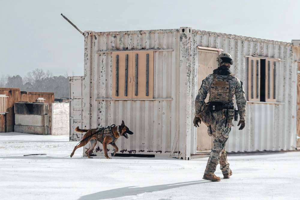 SouthComK9 handler and working dog clearing a snow-covered container facility during a live training scenario